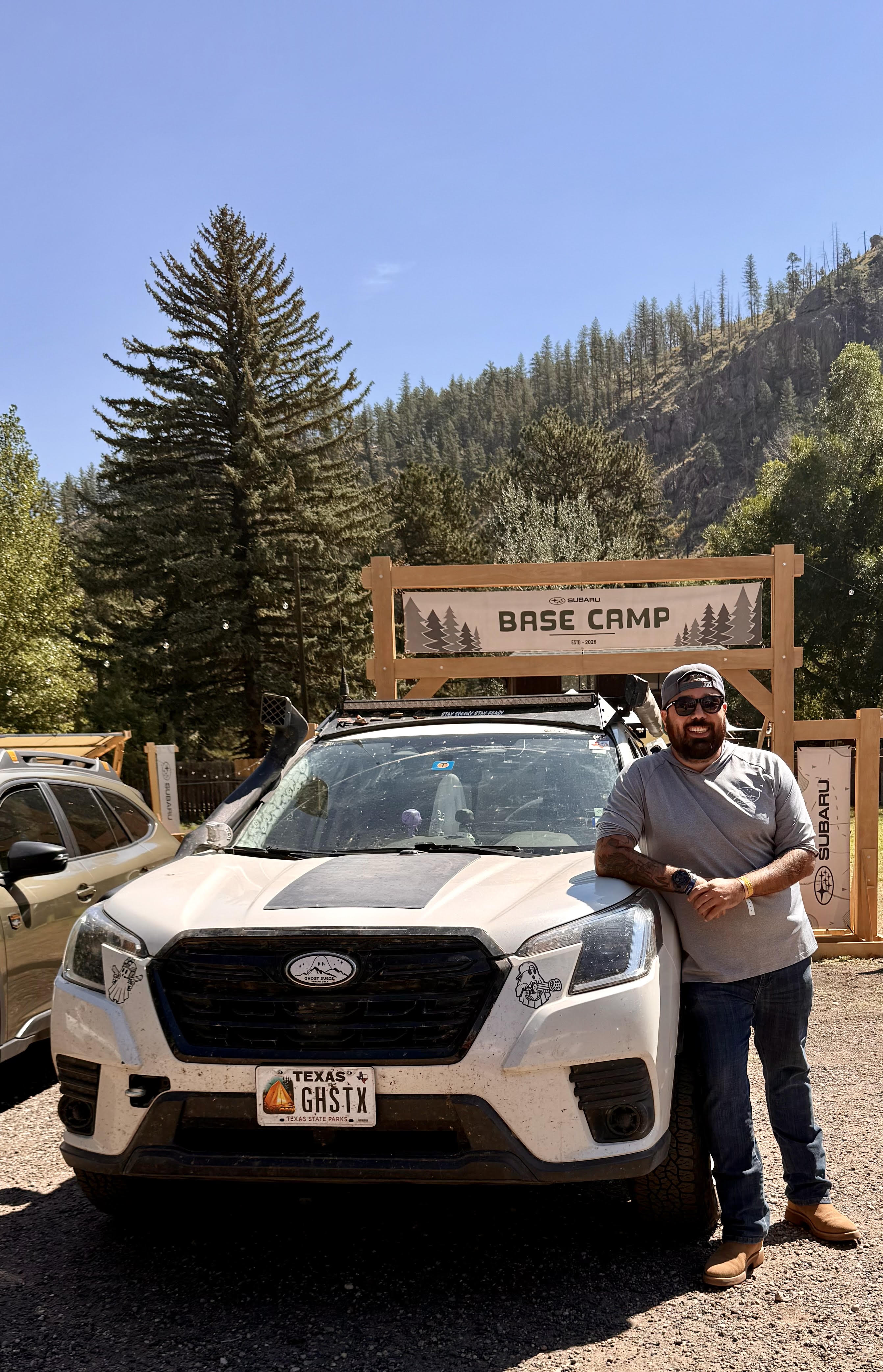 Roman leaning on the Ghost beneath the Subaru Base Camp sign